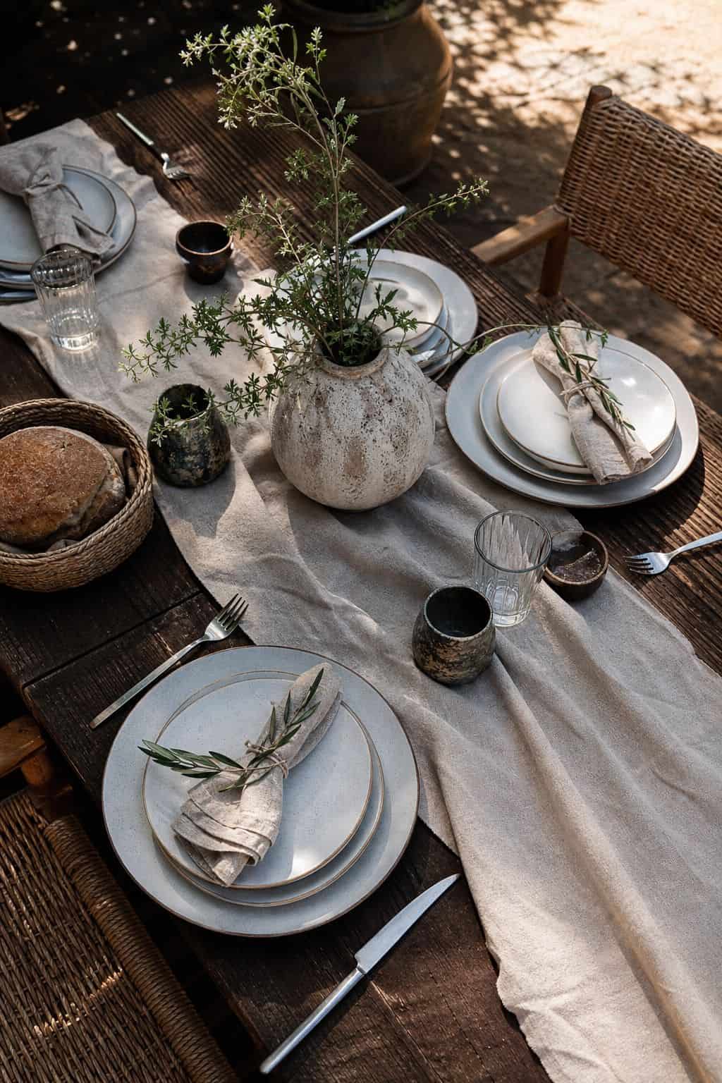 Summer table setting with a soft linen runner and layered neutral place settings.