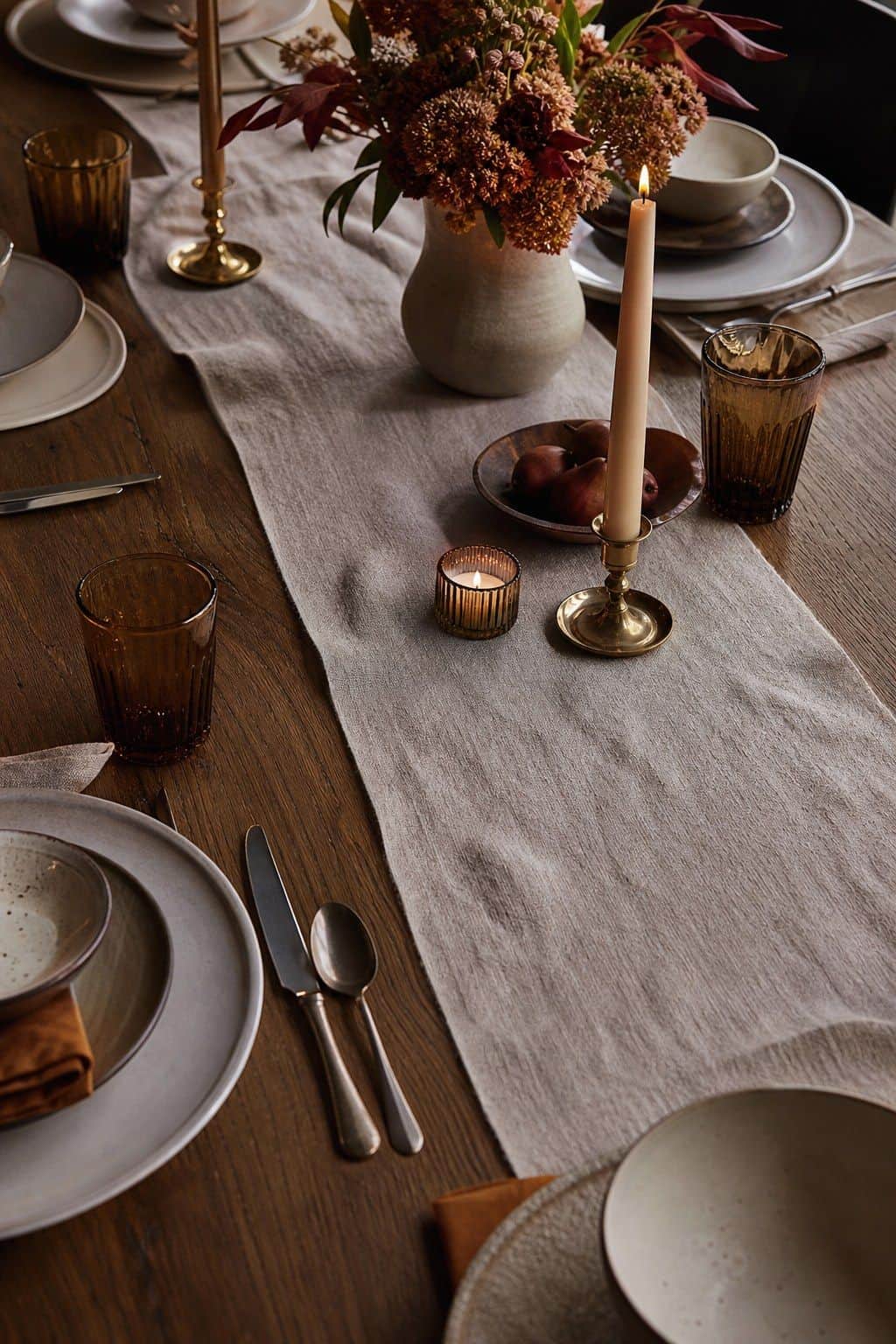 Friendsgiving table with a linen runner showing the wood table underneath.