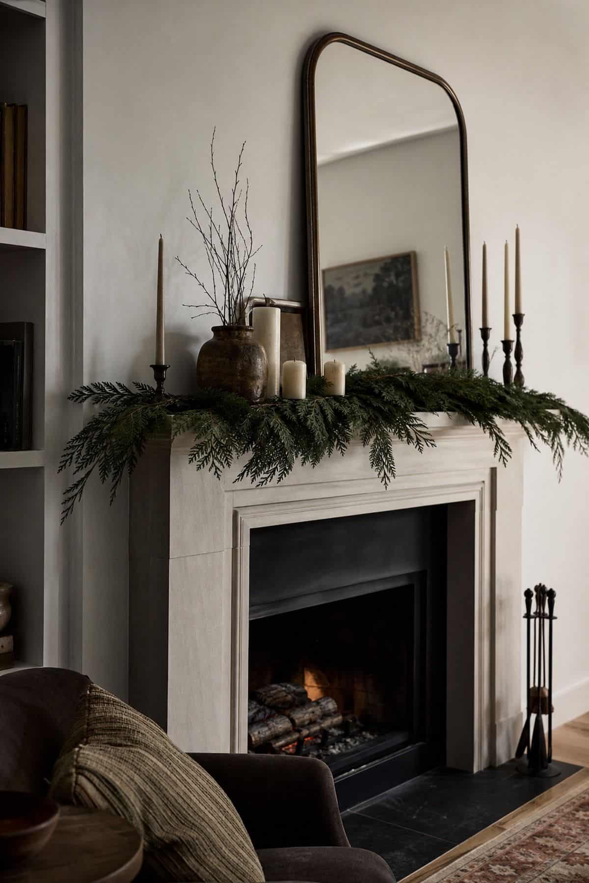 Winter mantel decor with a thin relaxed line of cedar and pine greenery across a winter fireplace mantel.
