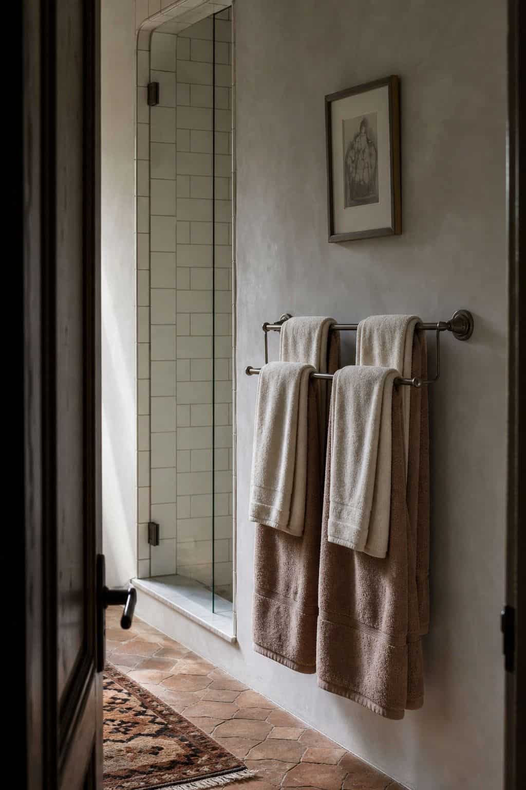 Double wall towel bar with layered cotton towels in a calm tiled bathroom.