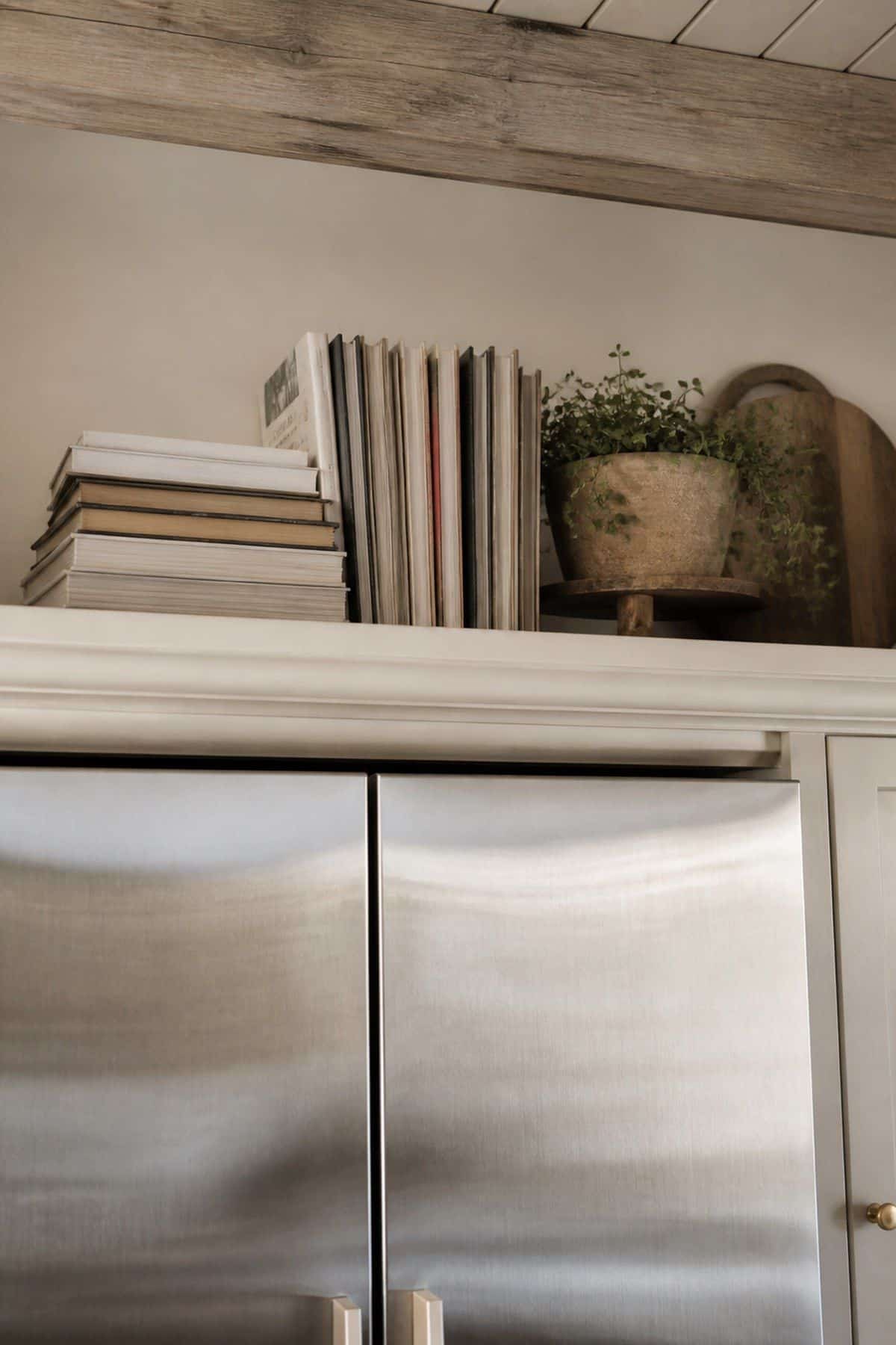 Showcase Cookbooks or Collections of Recipes shown as a realistic Pretty Wild World image for 15 Above Fridge Storage and Decor Ideas for a More Curated Home Aesthetic.