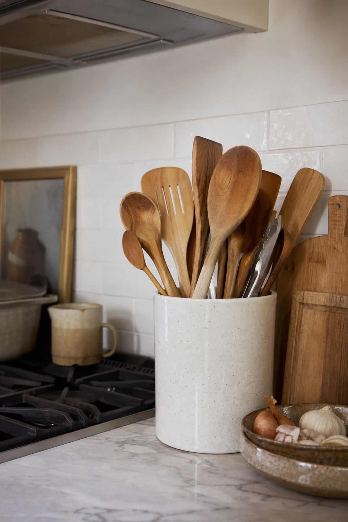 Keep Cooking Utensils in a Countertop Holder shown as a realistic Pretty Wild World image for 15 Kitchen Counter Organization Ideas for a Warm, Beautifully Styled Kitchen.