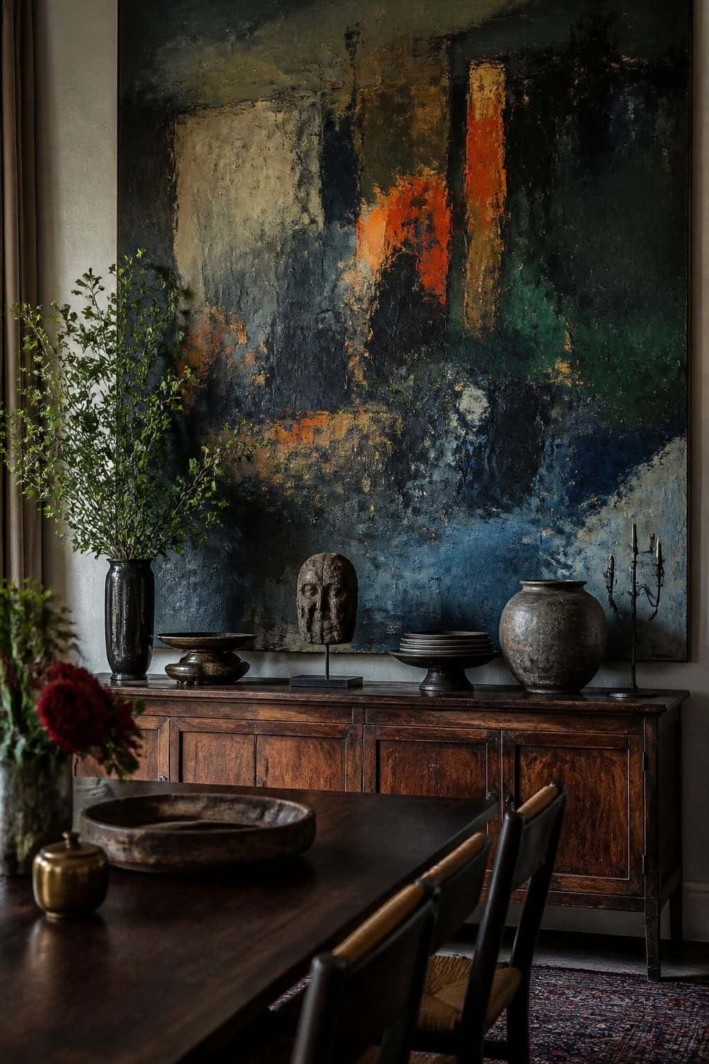 Editorial-style maximalist wall decor idea showing oversized statement art in a layered home interior with saturated color, collected objects, varied frames, tactile materials, and soft natural daylight. The scene feels realistic and lived in, with imperfect spacing, rich texture, and a bold wall treatment that demonstrates how to make a blank wall feel personal, abundant, and intentional without looking like a showroom. It shows how one large-scale artwork can carry a whole room with confi