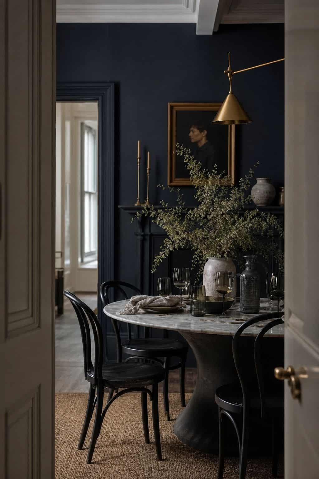 A midnight blue dining nook with brass lighting, black chairs, a marble-topped table, smoky glass, and ivory linen, styled in soft natural daylight to show a polished moody palette. The image gives readers a clear example of how deep blue and warm metal can make a small dining space feel elegant, sharp, atmospheric, and balanced with pale fabric, reflective finishes, and subtle texture. It keeps the palette clear for readers comparing navy, brass, black, marble, and linen.