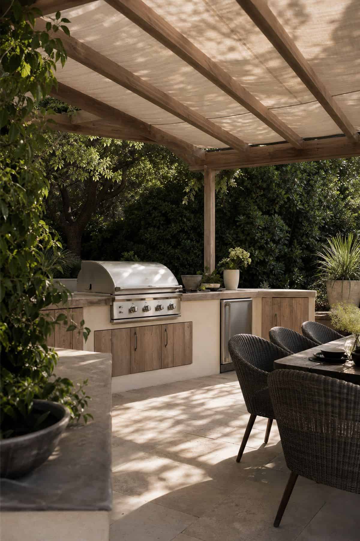 Install a pergola or shade sail to provide shelter from the sun shown as a realistic Pretty Wild World image for 15 Outdoor Kitchen Patio Decor Ideas for a Warm, Beautifully Styled Kitchen.