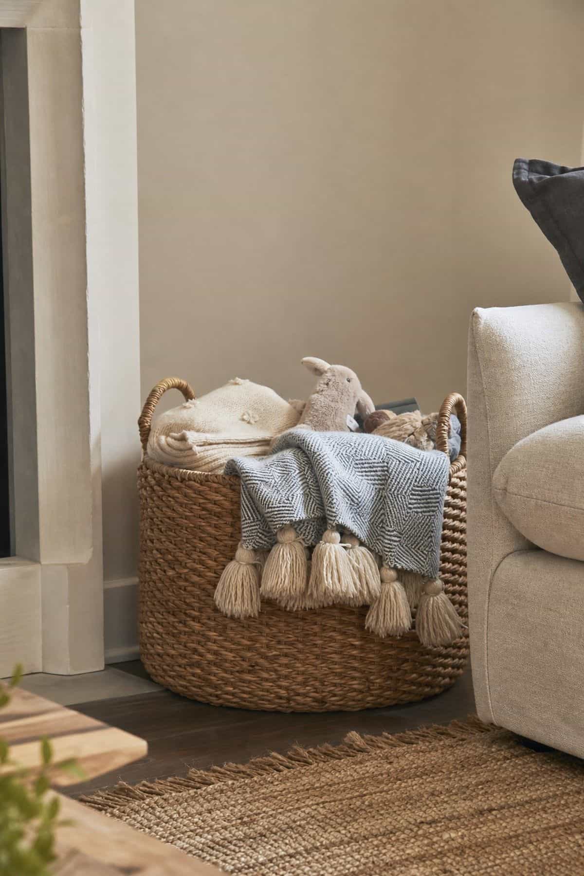 Use a Woven Basket for Organizing Blankets or Toys shown as a realistic Pretty Wild World image for 15 Room Corner Decor Ideas That Make Awkward Spaces Feel Intentional.