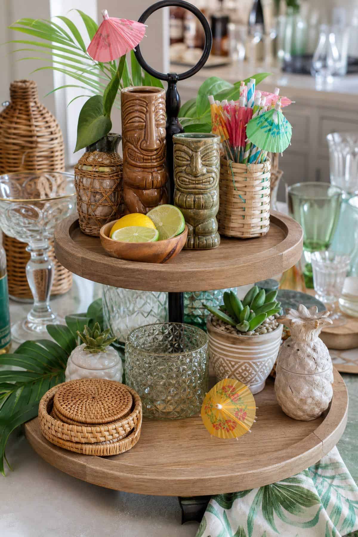 Include Mini Tiki Statues or Cocktail Umbrellas shown as a realistic Pretty Wild World image for 15 Summer Tiered Tray Decor Ideas for a Collected, Seasonal Home Aesthetic.