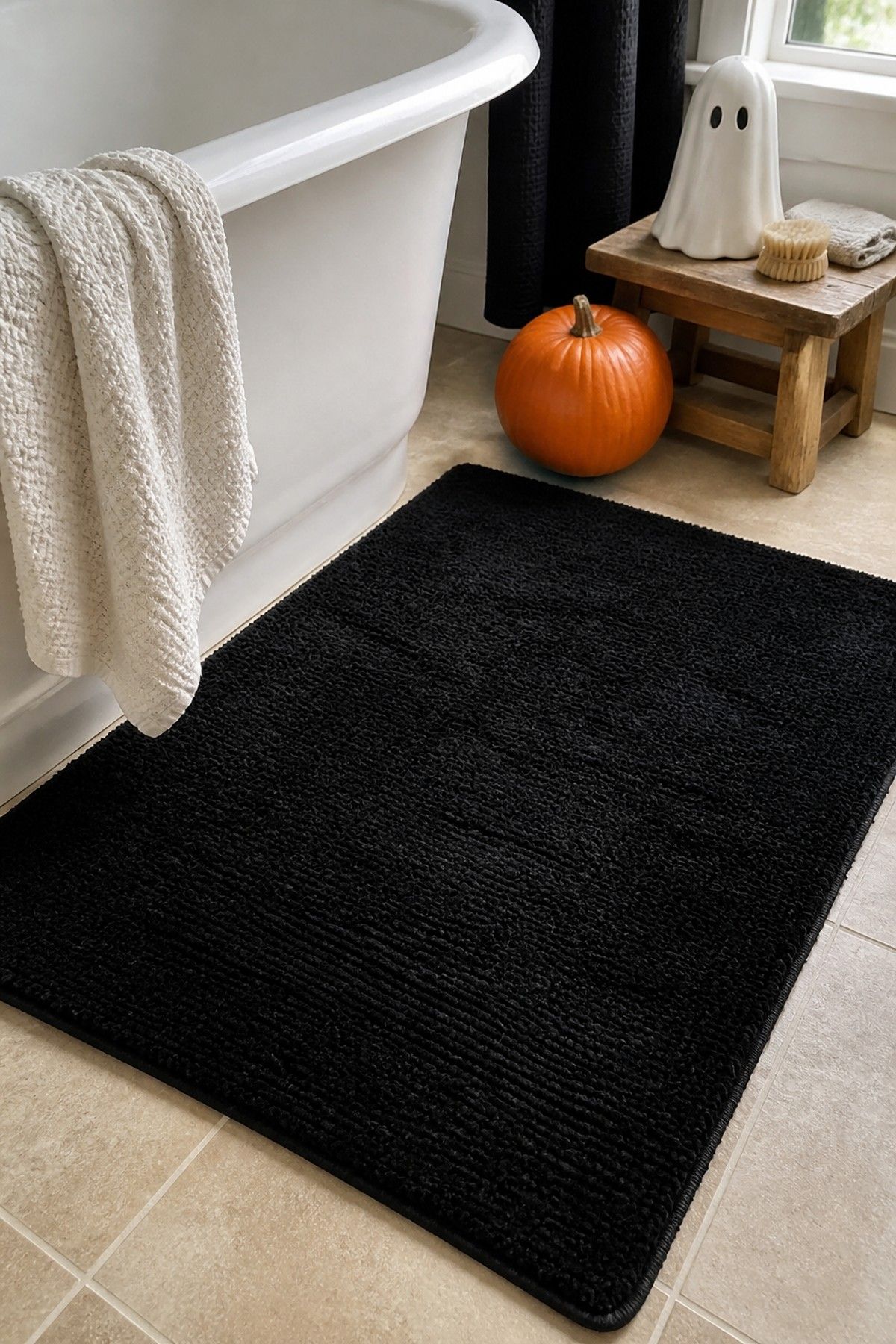 Washable black bath mat beside a tub with simple Halloween bathroom accents.